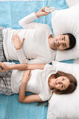 Young couple lying on electric heating pad in bedroom, top view © Pixel-Shot