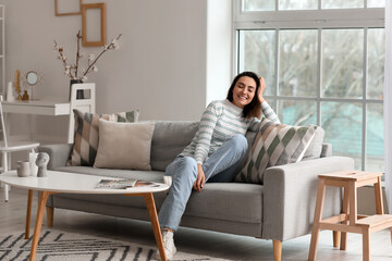 Young woman sitting on grey couch in living room