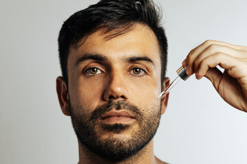 Middle-aged handsome man applying anti-aging face serum