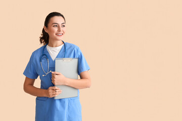 Female medical assistant with clipboard on beige background