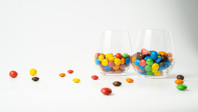 Colorful candy dragee in glasses on white background. Two jars of candies. Candy drink. Kids cocktails