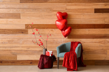 Interior of living room decorated for Valentine's Day with armchair, gift and balloons