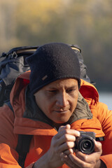 Obraz premium Portrait of traveler man at lake in autumn taking a photo with the digital camera