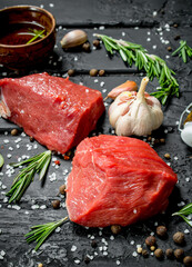 Raw meat. Sliced pieces of beef with spices and herbs on a wooden Board.