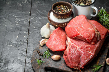 Raw meat. Pieces of beef with spices and herbs on a wooden Board.