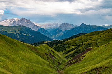 Alpine landscape with mountains and green meadows and a mountain range in the background. Italian Alps, Dolomites, Italy, Europe. Tourism and travel concept.