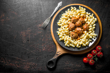 Pasta with meat balls and tomatoes on a branch.