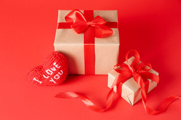 Gift boxes and knitted heart on red background. Valentine's Day celebration