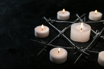 Burning candles and barbed wire in shape of David star on black background. International Holocaust Remembrance Day