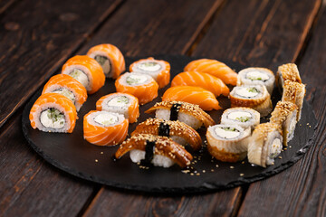 Sushi set from top on black background. An assortment of various maki nigiri and rolls seafood soy sauce