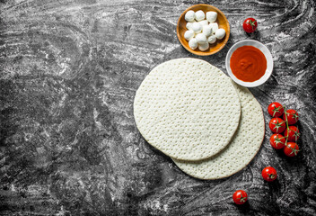 Raw pizza. Rolled out dough with tomato paste, tomatoes and cheese.