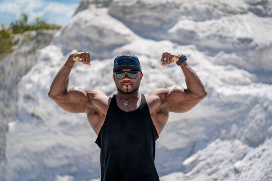 Young bodybuilder with srong muscles. Strong muscular man showing power outdoor.