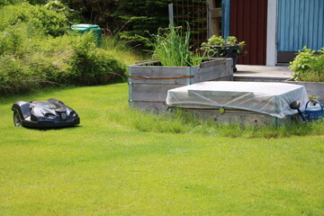 Robotic lawnmower and raised beds in the garden, Sweden - 562236362