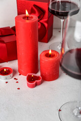 Burning candles, glasses of wine and gift boxes on light background, closeup. Valentine's Day celebration