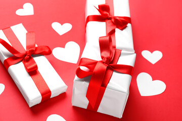 Gift boxes and paper hearts on red background, closeup. Valentine's Day celebration