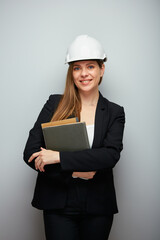Isolated portrait of woman engineer smiling and happy wearing safety helmet and black suit holding books or business paper.