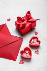 Composition with burning candles, gift box and envelopes on light background. Valentine's Day celebration
