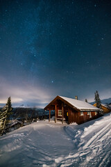 Milky Way stars under Cabin House in Norway. Christmas Night with Snow House Hytte