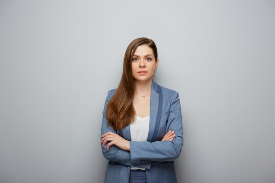 Serious woman in business suit standing with arms crossed.