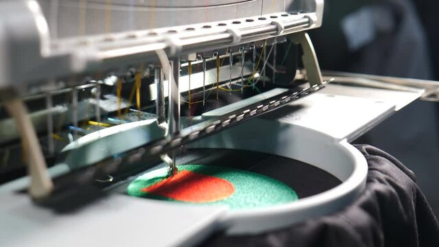 Embroidery machine in progress embroidery company logo on uniform in Textile Industry at Garment Manufacturers. Weaving machine for garment industry. Sewing workshop or tailoring factory. 4 k video