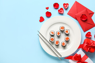Plate with sushi rolls, chopsticks, envelopes and gifts on blue background. Valentine's Day celebration