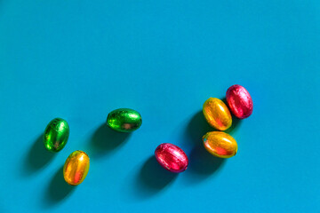 Easter chocolate eggs in foil on blue background. Top view
