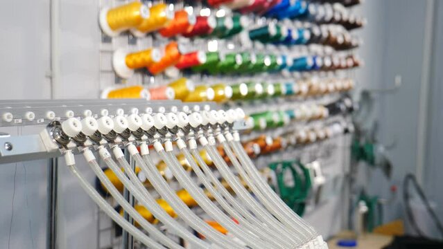 Rows spools of thread of different colors in industrial sewing factory. Textile Industry at Garment Manufacturers. Weaving machine for garment industry. Sewing workshop or tailoring factory. 4 k video