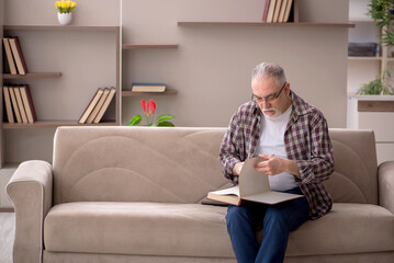 Old man reading book at home