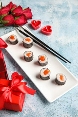 Plate with sushi rolls, chopsticks and gifts on grunge background, closeup. Valentine's Day celebration