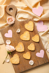 Composition with wooden board of sweet heart shaped cookies and rose flowers on color background. Valentines Day celebration