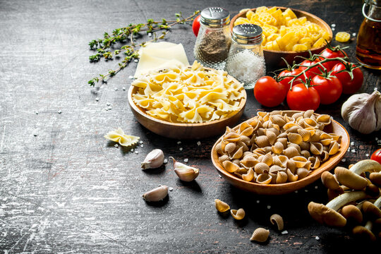 Different types of raw paste in bowls with tomatoes, garlic and mushrooms.