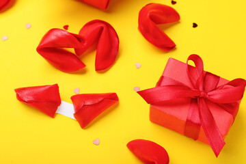 Red fortune cookies and gift box on yellow background. Valentine's Day celebration