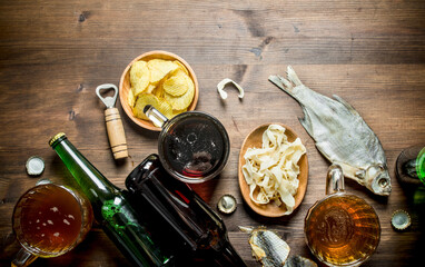 Beer with chips and squid rings in bowl and dried fish.