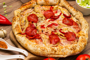 Sausage and vegetable pizza served on round wooden board