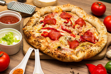 Sausage and vegetable pizza served on round wooden board