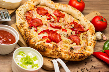 Sausage and vegetable pizza served on round wooden board