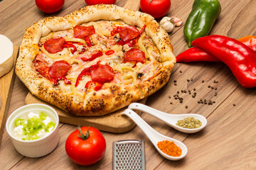 Sausage and vegetable pizza served on round wooden board