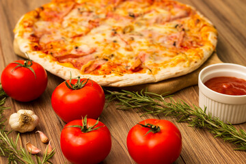 Freshly baked pizza with ham, tomato, and cheese