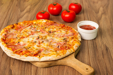 Freshly baked pizza with ham, tomato, and cheese