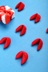 Fortune cookies with gift on blue background, closeup. Valentine's Day celebration