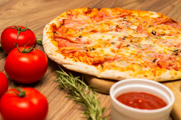 Freshly baked pizza with ham, tomato, and cheese
