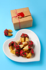 Plate of fortune cookies with gift on blue background. Valentine's Day celebration