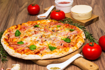 Freshly baked pizza with ham, tomato, and cheese