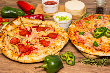 Two different pizza with ingredients on rustic background. Pepperoni pizza and pizza Capricciosa with mozzarella cheese, ham, tomato sauce, salami, mushroom, pepper, spices and fresh basil