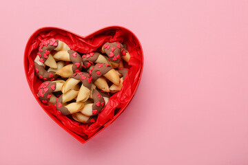 Heart-shaped gift box with fortune cookies on pink background. Valentine's Day celebration