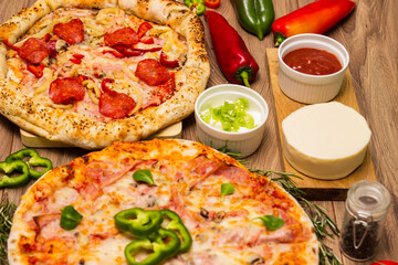 Two different pizza with ingredients on rustic background. Pepperoni pizza and pizza Capricciosa with mozzarella cheese, ham, tomato sauce, salami, mushroom, pepper, spices and fresh basil