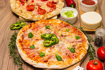 Two different pizza with ingredients on rustic background. Pepperoni pizza and pizza Capricciosa with mozzarella cheese, ham, tomato sauce, salami, mushroom, pepper, spices and fresh basil