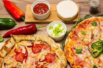 Two different pizza with ingredients on rustic background. Pepperoni pizza and pizza Capricciosa with mozzarella cheese, ham, tomato sauce, salami, mushroom, pepper, spices and fresh basil