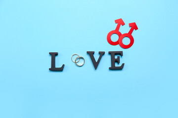 Word LOVE with wedding rings and man symbols on blue background. Valentine's Day celebration
