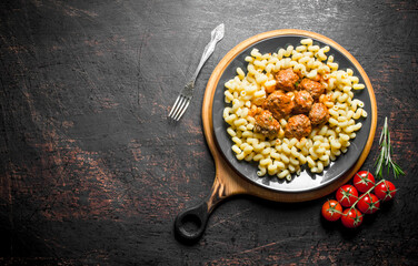 Pasta with meat balls and tomatoes on a branch.